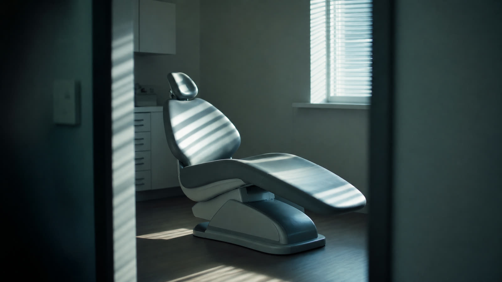 Un sillón odontológico vacío en un consultorio, con luz de la mañana entrando por la persiana.